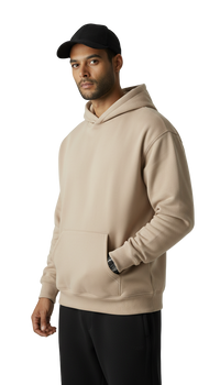 Man wearing a beige hoodie and black cap on a white background
