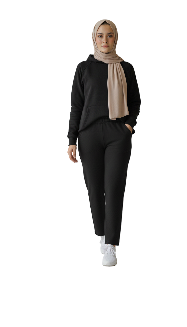 Person wearing a black outfit with a beige hijab on a plain background