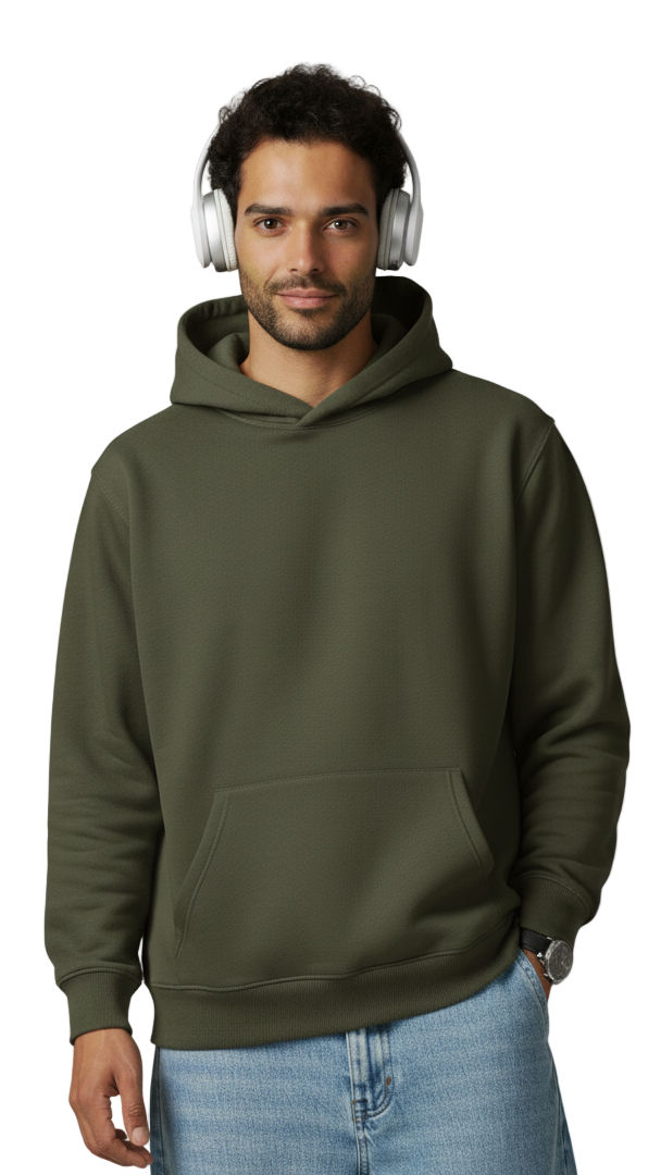 Man wearing an olive green hoodie and blue jeans with headphones on a plain background